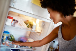 Shot of a young woman taking food out of the fridge at home