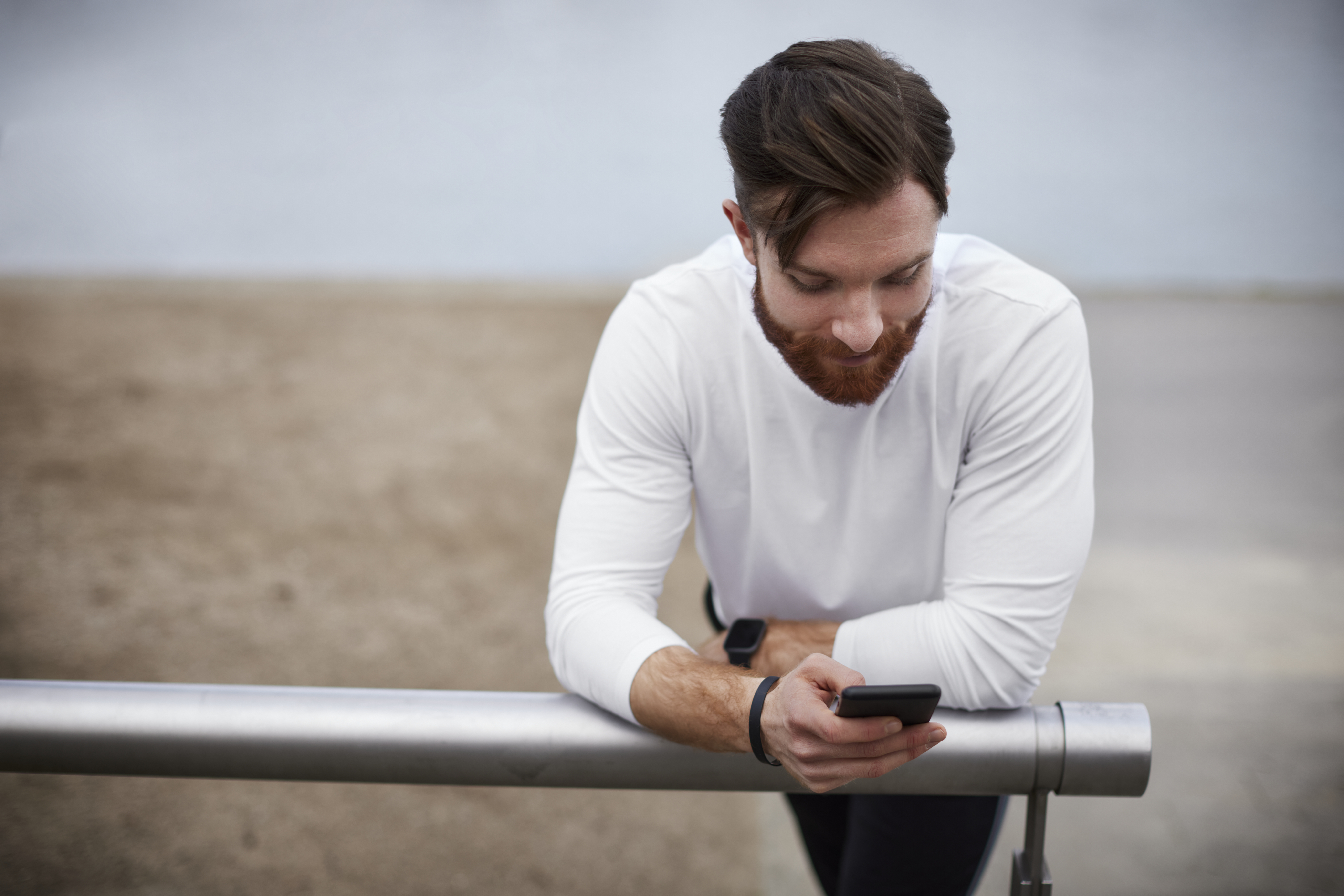 Young man leaning on a railing using smartphone